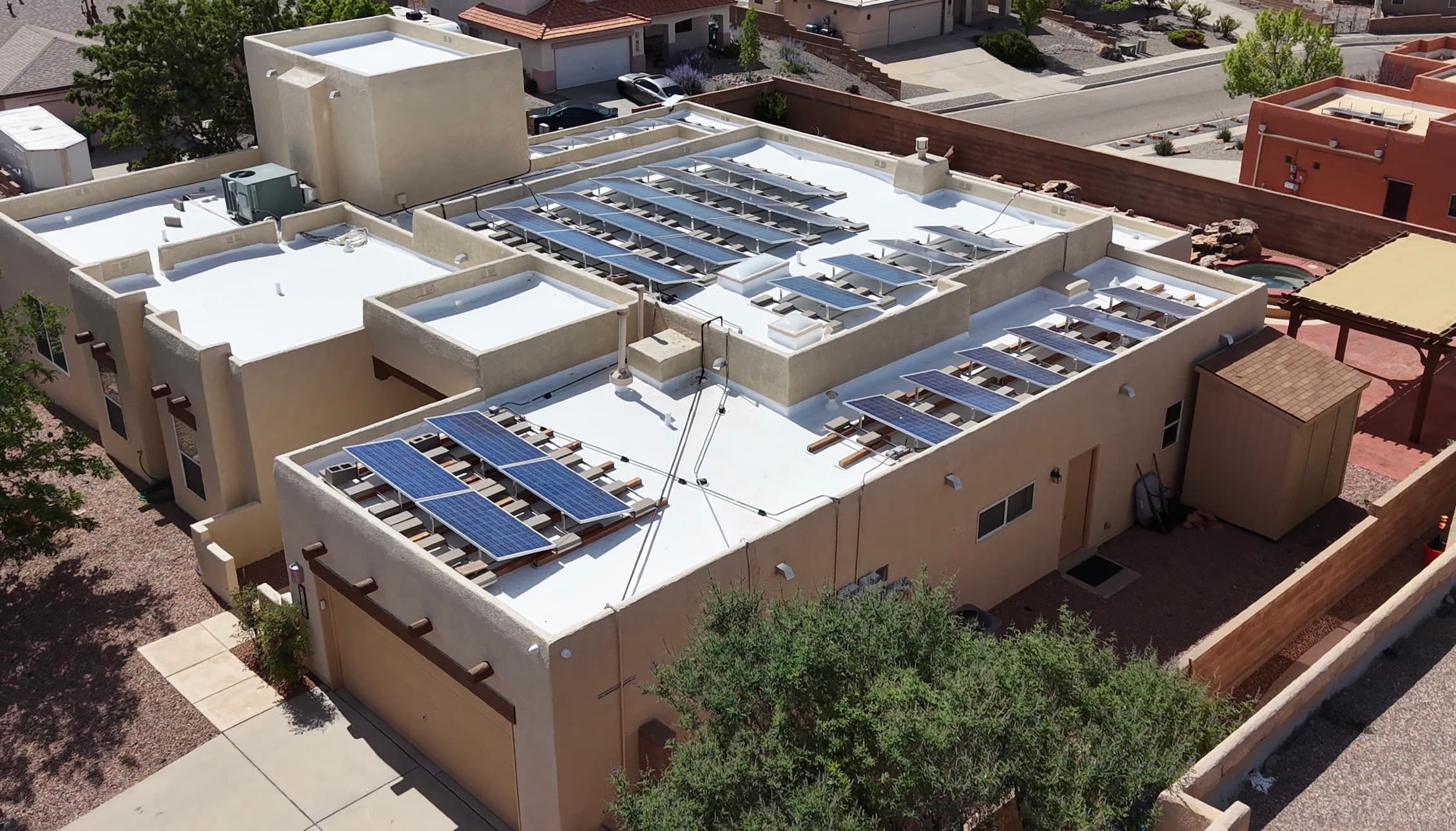 Aerial view of solar panels reinstalled on a newly re-roofed flat roof in Albuquerque by Lobo Construction & Electric